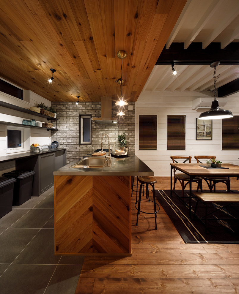 Foto på ett mellanstort 60 tals linjärt kök med öppen planlösning, med en integrerad diskho, öppna hyllor, grå skåp, bänkskiva i rostfritt stål, grått stänkskydd, stänkskydd i porslinskakel och en halv köksö