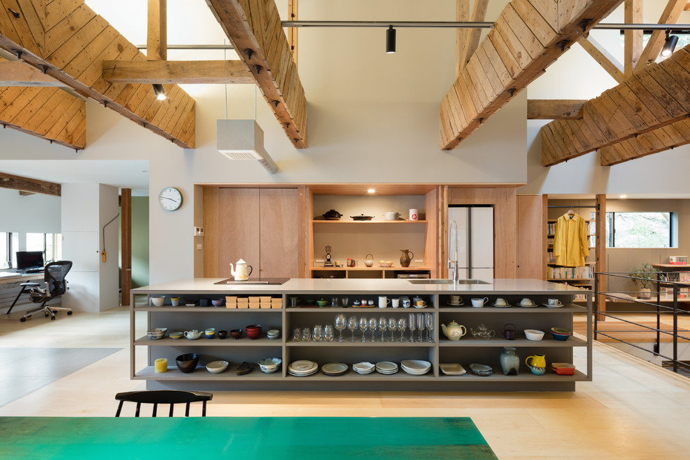 Ejemplo de cocina lineal de estilo zen abierta con electrodomésticos blancos, suelo de madera clara y una isla