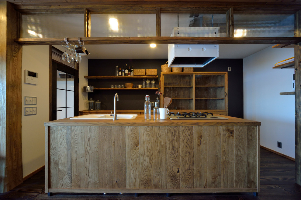 Einzeilige Industrial Küche mit hellbraunen Holzschränken, Arbeitsplatte aus Holz, dunklem Holzboden, Kücheninsel und braunem Boden in Yokohama