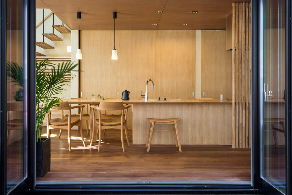 Immagine di una cucina minimalista con lavello a vasca singola, ante lisce, ante in legno scuro, top in legno, pavimento in legno massello medio e pavimento marrone
