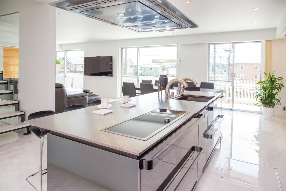 コンテンポラリースタイルのおしゃれなキッチン (ステンレスキャビネット、ステンレスカウンター、一体型シンク、メタリックのキッチンパネル、黒い調理設備、白い床) の写真