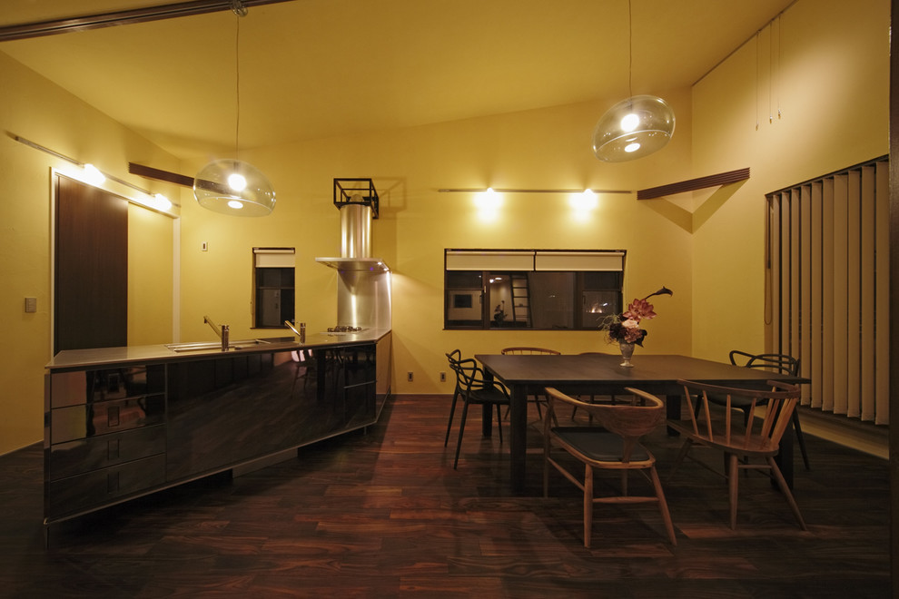 他の地域にあるミッドセンチュリースタイルのおしゃれなキッチン (一体型シンク、グレーのキャビネット、ステンレスカウンター、グレーのキッチンパネル、シルバーの調理設備、茶色い床) の写真