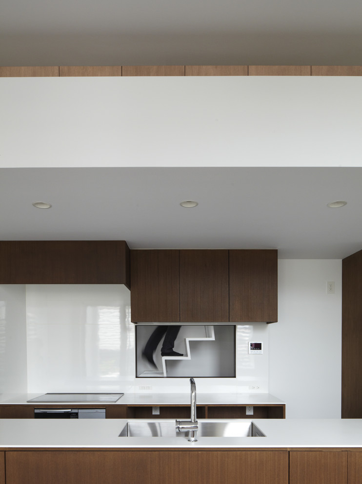 Inspiration pour une cuisine parallèle minimaliste en bois foncé avec un évier encastré, un placard à porte plane, une crédence blanche et un électroménager en acier inoxydable.