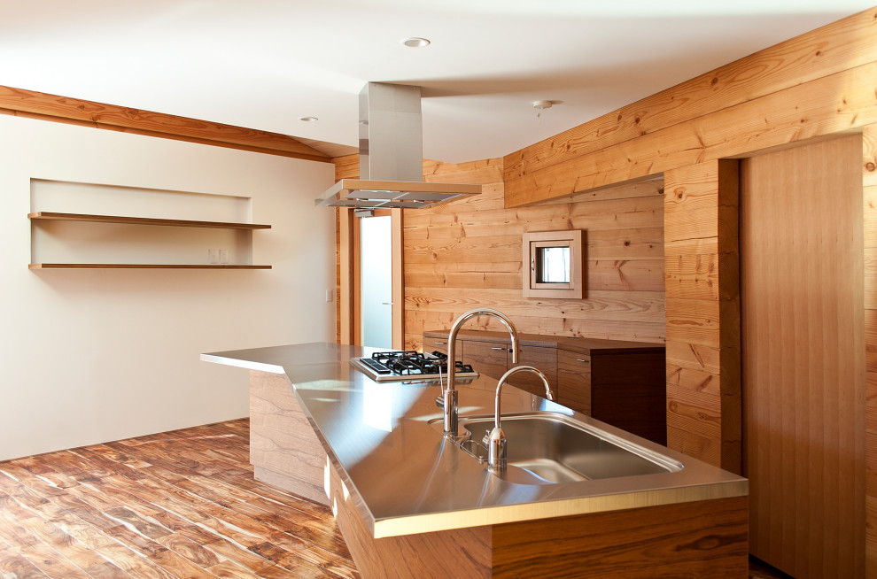 Idéer för att renovera ett funkis linjärt kök med öppen planlösning, med bänkskiva i rostfritt stål, skåp i mellenmörkt trä, mörkt trägolv, en köksö, en integrerad diskho, stänkskydd i trä och integrerade vitvaror