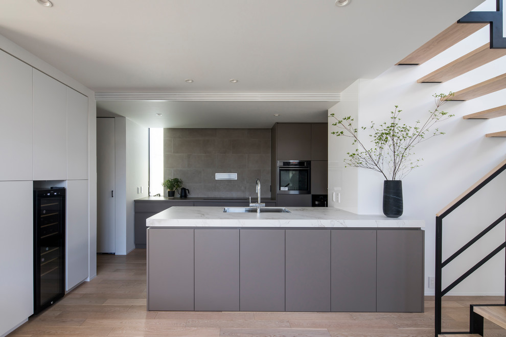Example of a mid-sized minimalist galley porcelain tile open concept kitchen design in Nagoya with beige cabinets, tile countertops, beige backsplash, ceramic backsplash, an island and white countertops