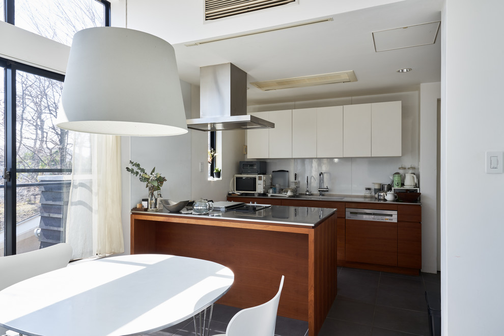 This is an example of a contemporary kitchen in Tokyo Suburbs with an integrated sink, flat-panel cabinets, medium wood cabinets, stainless steel worktops, a breakfast bar and grey floors.