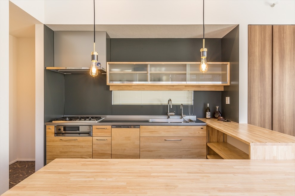 Exemple d'une cuisine ouverte moderne en U et bois brun de taille moyenne avec un placard sans porte, un plan de travail en inox, un évier 1 bac, un sol gris et un plan de travail beige.
