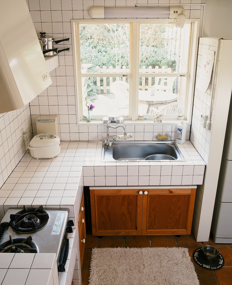 Foto de cocina de estilo de casa de campo sin isla con armarios con paneles con relieve, puertas de armario de madera oscura y electrodomésticos blancos