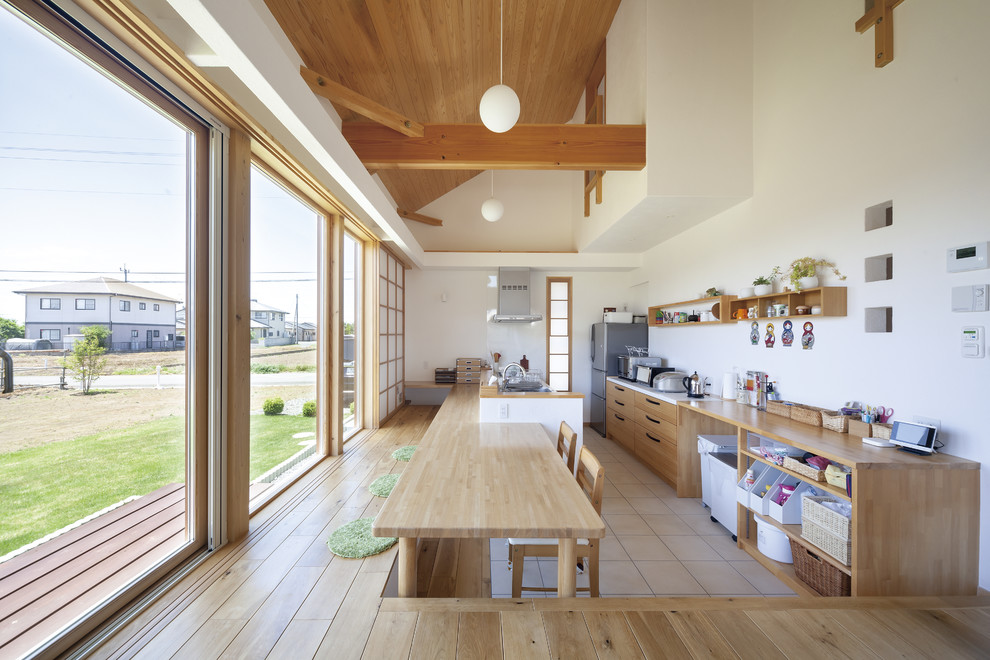 Идея дизайна: параллельная кухня-гостиная в восточном стиле с плоскими фасадами, фасадами цвета дерева среднего тона, деревянной столешницей, белым фартуком, полуостровом, бежевым полом и коричневой столешницей