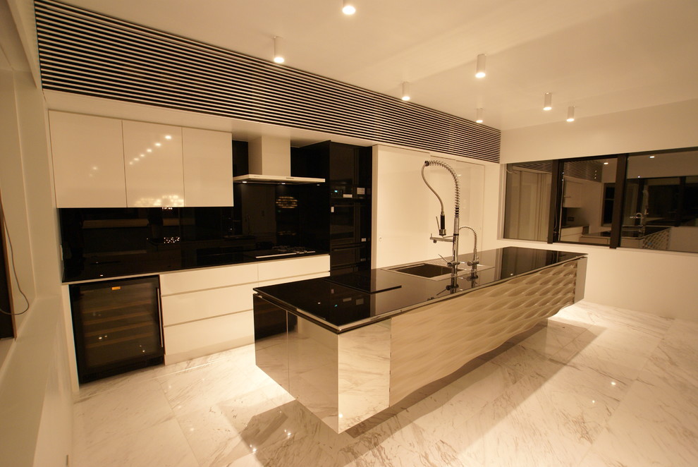 Cette photo montre une cuisine parallèle tendance avec un évier posé, un placard à porte plane, des portes de placard blanches, un électroménager noir et îlot.