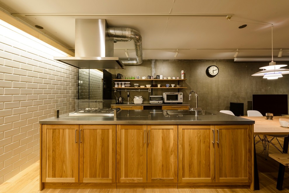 Foto de cocina lineal industrial con fregadero de un seno, armarios con paneles empotrados, puertas de armario de madera oscura, encimera de acero inoxidable, suelo de madera en tonos medios, una isla y suelo marrón