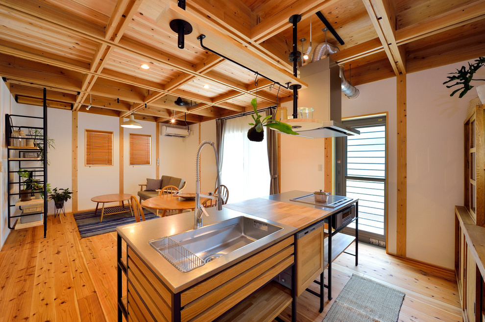 Foto de cocina lineal de estilo zen abierta con fregadero de un seno, encimera de acero inoxidable, suelo de madera en tonos medios, una isla y suelo marrón