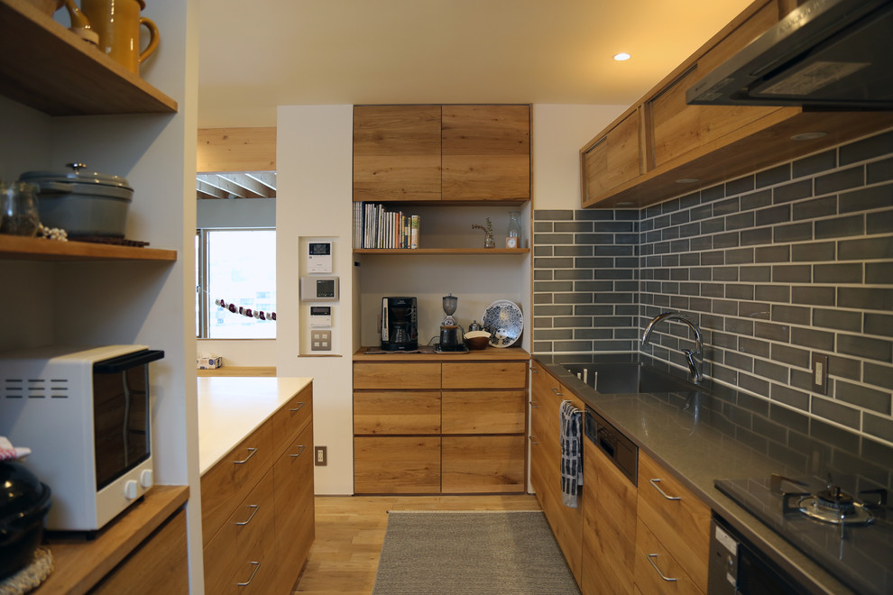 Inredning av ett skandinaviskt avskilt u-kök, med en enkel diskho, släta luckor, skåp i mellenmörkt trä, bänkskiva i rostfritt stål, grått stänkskydd, stänkskydd i keramik, ljust trägolv, en halv köksö och brunt golv