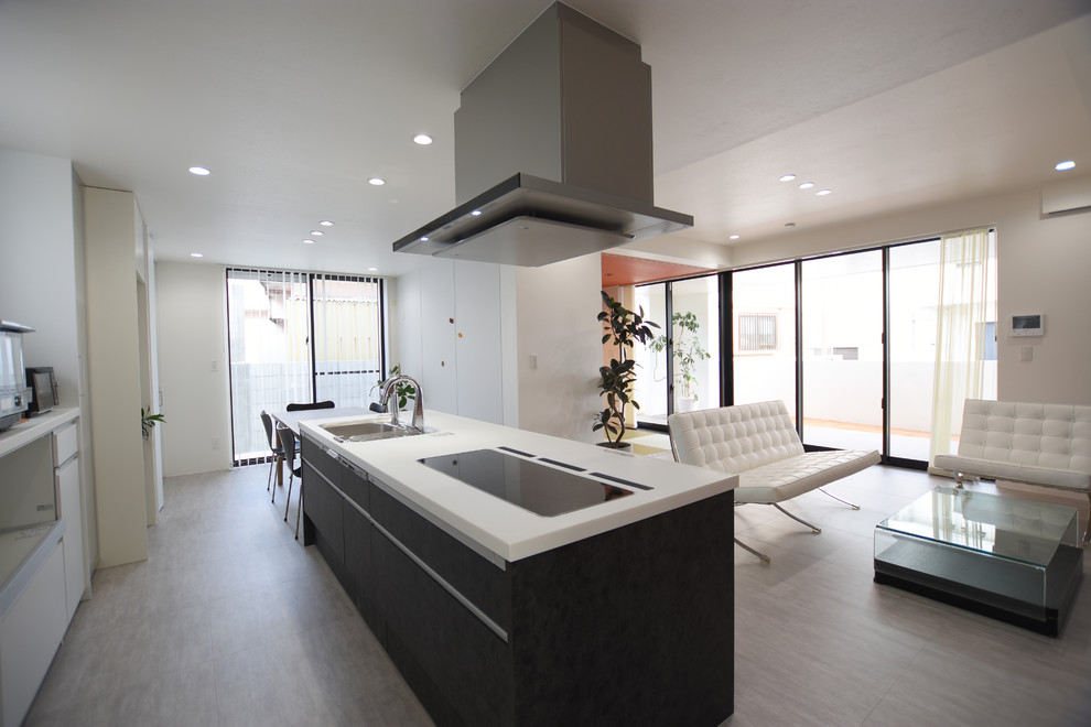Cette image montre une cuisine ouverte linéaire minimaliste avec un sol en vinyl, un sol gris, un évier 1 bac, un placard à porte plane, des portes de placard noires, îlot et un plan de travail blanc.