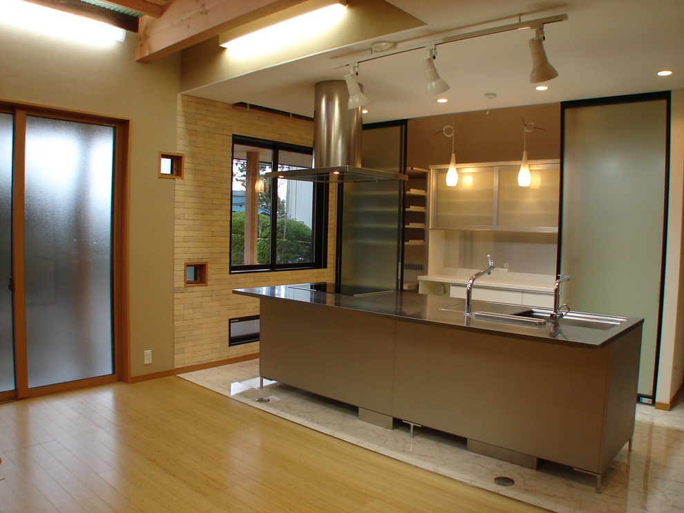 Exempel på ett asiatiskt kök, med en integrerad diskho, luckor med glaspanel, bänkskiva i rostfritt stål och en köksö