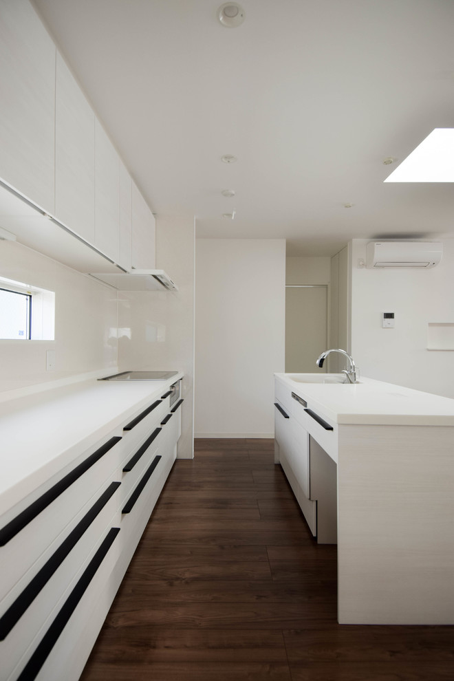 Esempio di una cucina moderna di medie dimensioni con lavello sottopiano, ante a filo, ante bianche, top in superficie solida, paraspruzzi bianco, parquet scuro, pavimento beige e top bianco