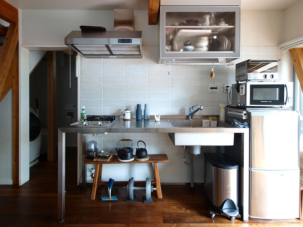 Einzeilige, Kleine Industrial Wohnküche mit offenen Schränken, Edelstahl-Arbeitsplatte, Küchenrückwand in Weiß, braunem Boden, integriertem Waschbecken, Küchengeräten aus Edelstahl und dunklem Holzboden in Tokio