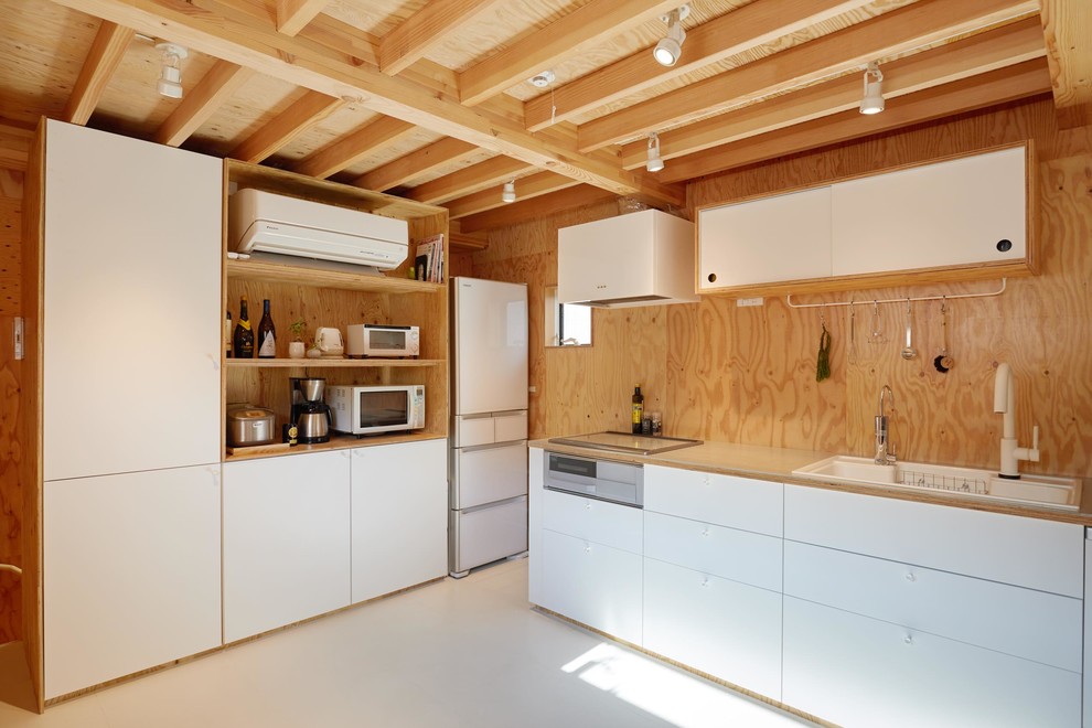 Modelo de cocina lineal de estilo zen pequeña abierta sin isla con puertas de armario blancas, salpicadero blanco, salpicadero de madera, electrodomésticos de acero inoxidable, suelo blanco y encimeras grises
