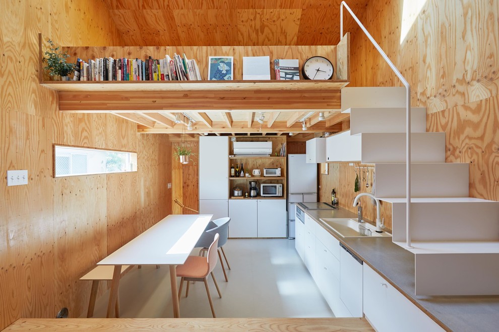 Small world-inspired l-shaped open plan kitchen in Tokyo with white cabinets, no island, grey worktops, a built-in sink, flat-panel cabinets, brown splashback, wood splashback, white appliances and white floors.