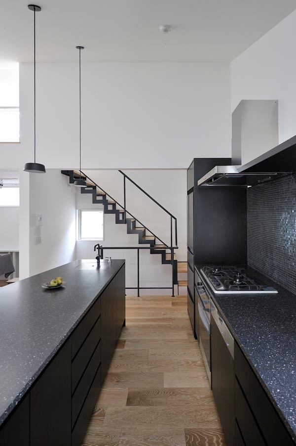 Esempio di una cucina minimalista con lavello integrato, ante nere, top in superficie solida e parquet chiaro