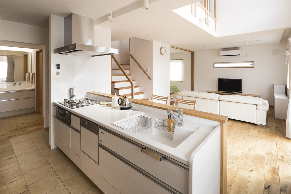 This is an example of a scandinavian single-wall open plan kitchen in Other with a single-bowl sink, beaded cabinets, composite countertops, no island, white worktops, white splashback, medium hardwood flooring and brown floors.