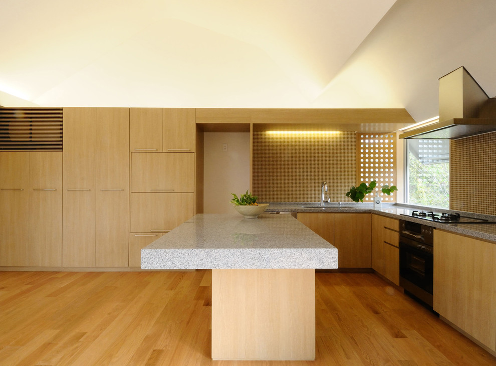 Inspiration for a world-inspired l-shaped open plan kitchen with a submerged sink, flat-panel cabinets, light wood cabinets, beige splashback, stainless steel appliances, light hardwood flooring, an island and beige floors.