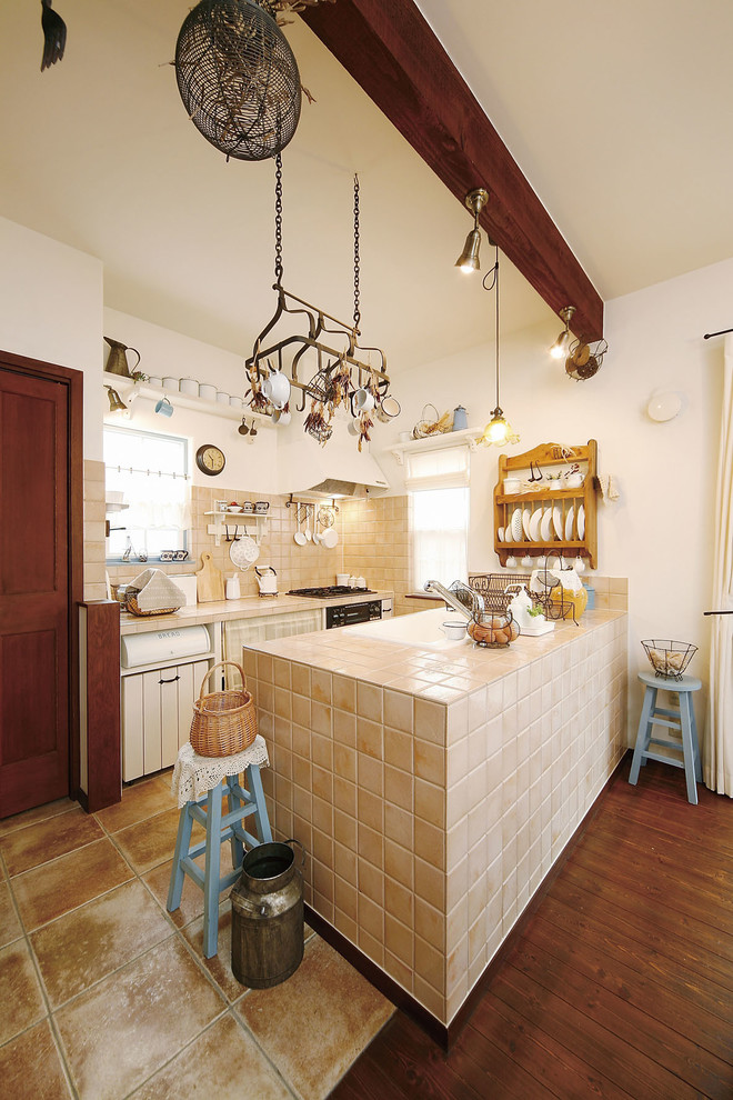 Exemple d'une cuisine ouverte parallèle méditerranéenne avec un évier 1 bac, plan de travail carrelé, une crédence beige, une crédence en céramique, tomettes au sol, une péninsule, un sol marron et un plan de travail beige.