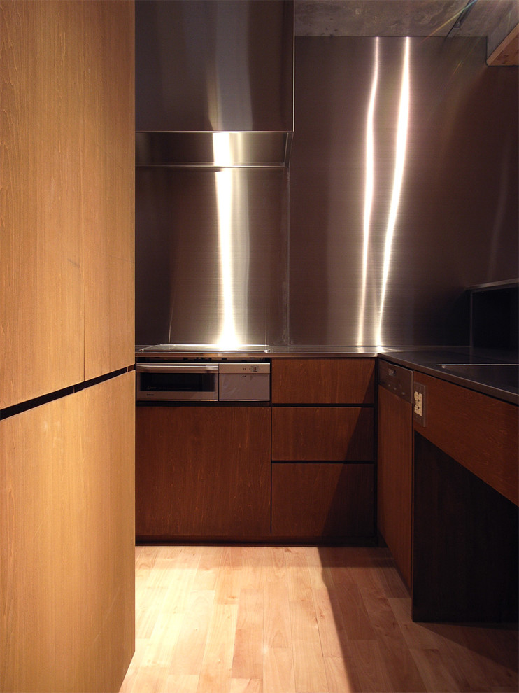 Idée de décoration pour une cuisine minimaliste en L avec un évier intégré, un plan de travail en inox, une crédence grise, un électroménager de couleur, un sol en bois brun et îlot.