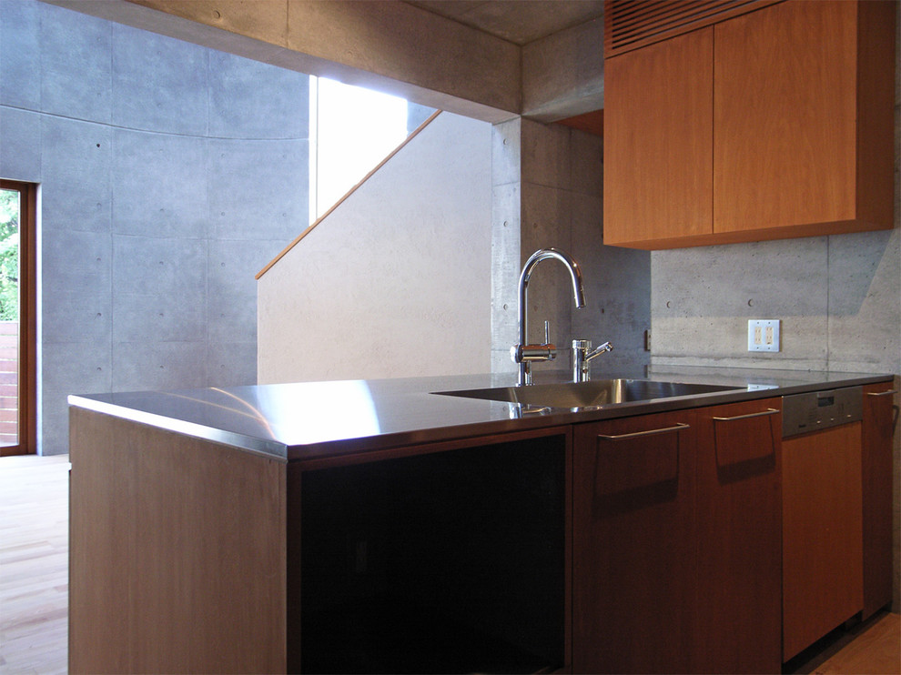 Modern inredning av ett kök, med en integrerad diskho, bänkskiva i rostfritt stål, grått stänkskydd, färgglada vitvaror, mellanmörkt trägolv och en halv köksö