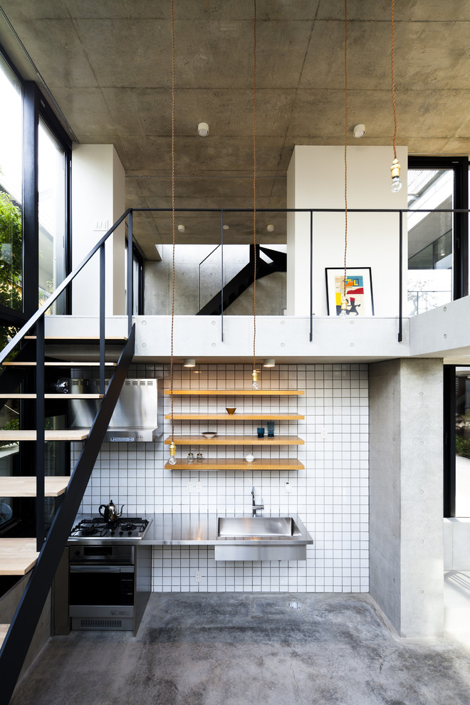 Inspiration för små moderna linjära kök och matrum, med en integrerad diskho, öppna hyllor, skåp i ljust trä, bänkskiva i rostfritt stål, vitt stänkskydd, rostfria vitvaror och betonggolv