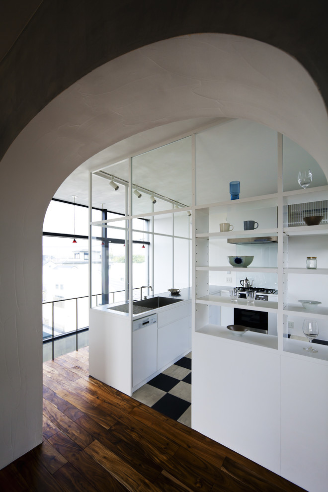 На фото: отдельная, угловая кухня в современном стиле с врезной мойкой, плоскими фасадами, белыми фасадами и черной техникой