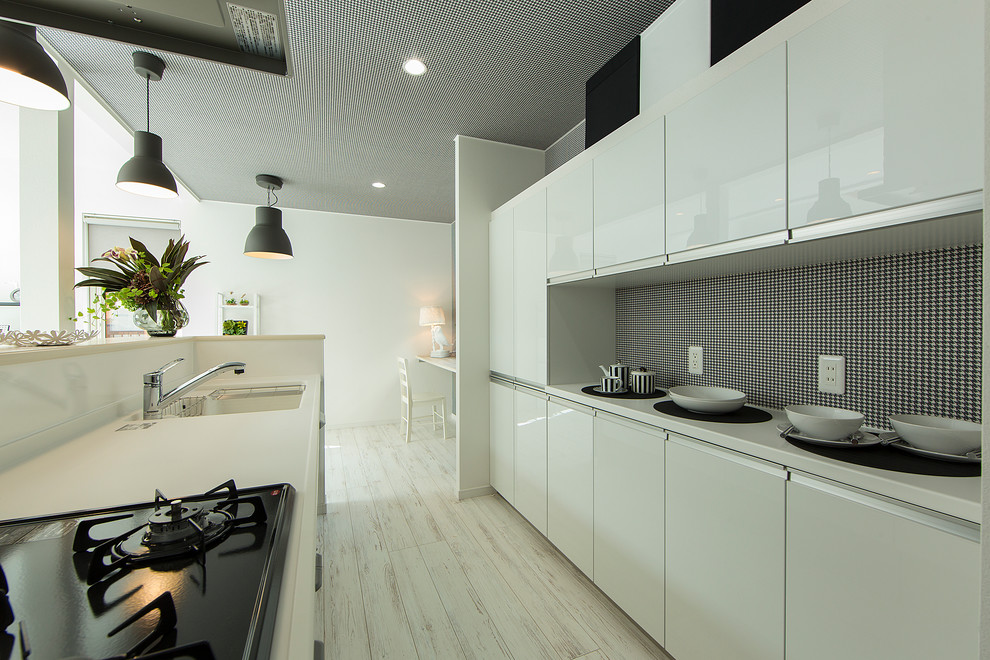 Foto di una cucina design con lavello sottopiano, ante lisce, ante bianche, paraspruzzi bianco, elettrodomestici neri e pavimento in legno verniciato