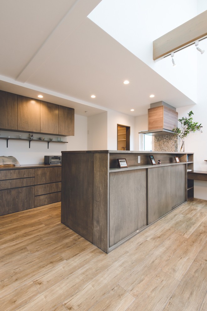 Design ideas for a large scandi galley open plan kitchen in Sapporo with flat-panel cabinets, light wood cabinets, a breakfast bar, black appliances, light hardwood flooring and a submerged sink.