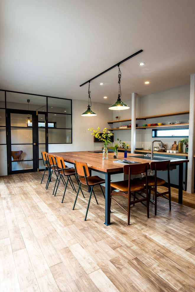 Exempel på ett modernt linjärt kök med öppen planlösning, med en undermonterad diskho, träbänkskiva, en köksö, släta luckor, blå skåp, ljust trägolv, beiget golv och grått stänkskydd