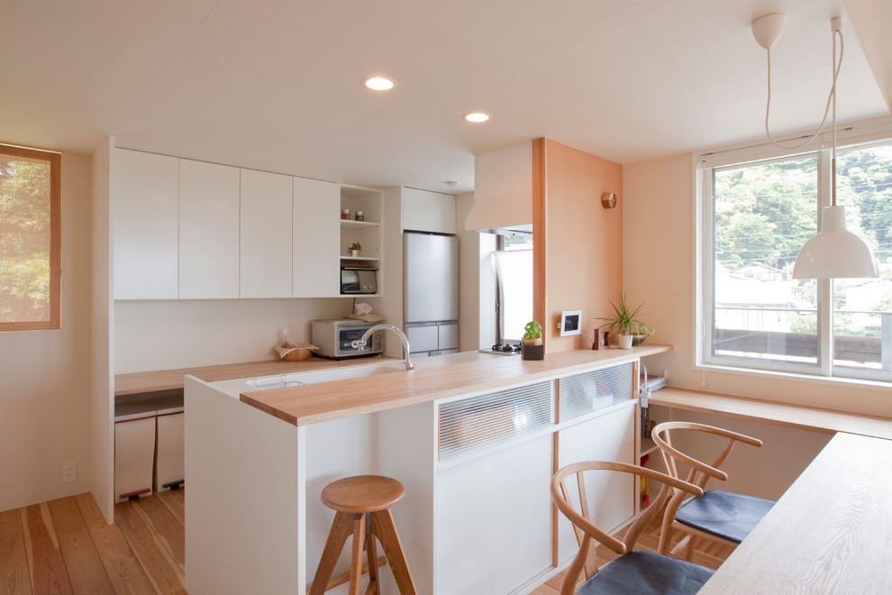 Источник вдохновения для домашнего уюта: кухня в стиле модернизм с монолитной мойкой, плоскими фасадами, белыми фасадами, паркетным полом среднего тона, коричневым полом и коричневой столешницей