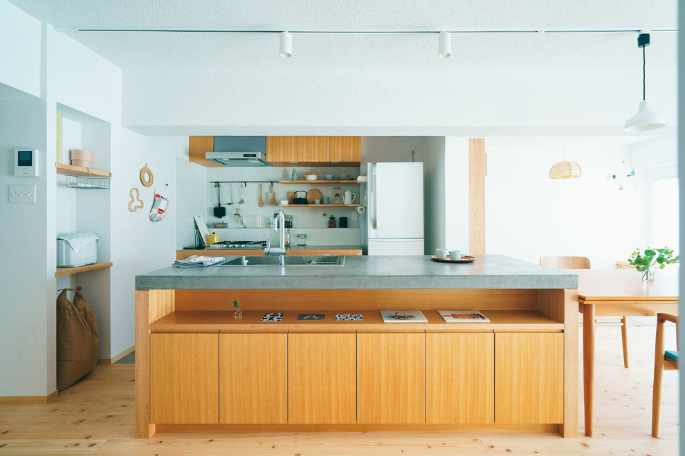 Diseño de cocina moderna abierta con fregadero de un seno, armarios con paneles lisos, puertas de armario de madera oscura, suelo de madera clara, una isla y suelo beige