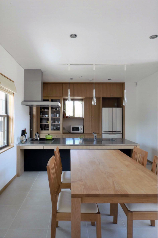 Immagine di una cucina scandinava con ante in legno chiaro, top in acciaio inossidabile, paraspruzzi in legno e pavimento in gres porcellanato