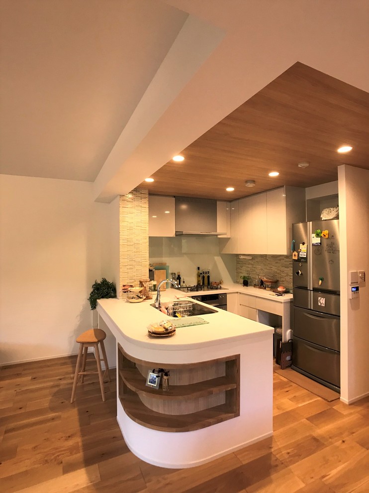 東京23区にある小さな北欧スタイルのおしゃれなキッチン (アンダーカウンターシンク、フラットパネル扉のキャビネット、白いキャビネット、人工大理石カウンター、ベージュキッチンパネル、セラミックタイルのキッチンパネル、シルバーの調理設備、無垢フローリング、アイランドなし、ベージュの床、白いキッチンカウンター) の写真