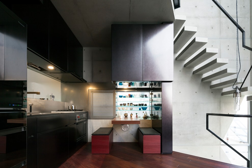 Example of an urban single-wall dark wood floor open concept kitchen design in Tokyo with an undermount sink, flat-panel cabinets, black cabinets, metallic backsplash, black appliances and no island