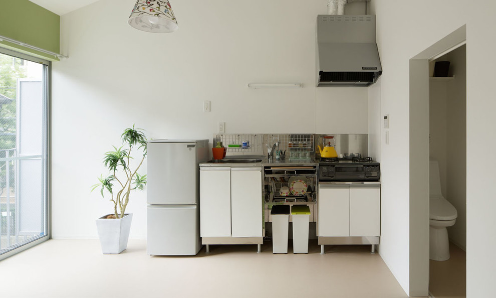 Inspiration för små industriella linjära kök med öppen planlösning, med släta luckor, vita skåp, stänkskydd med metallisk yta, vita vitvaror och en integrerad diskho