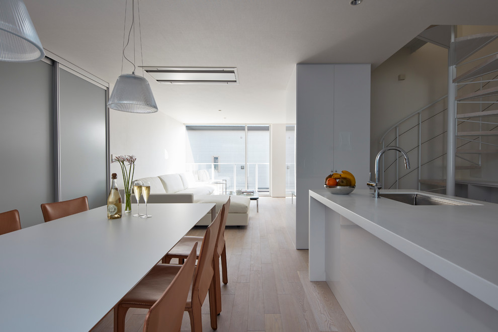 Imagen de cocina lineal moderna abierta con fregadero bajoencimera, electrodomésticos de acero inoxidable, suelo de madera clara y una isla