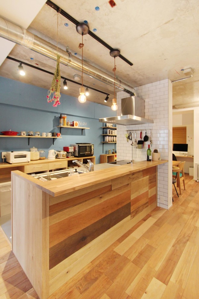 東京23区にある北欧スタイルのおしゃれなアイランドキッチン (シングルシンク、ステンレスカウンター、無垢フローリング、茶色い床) の写真