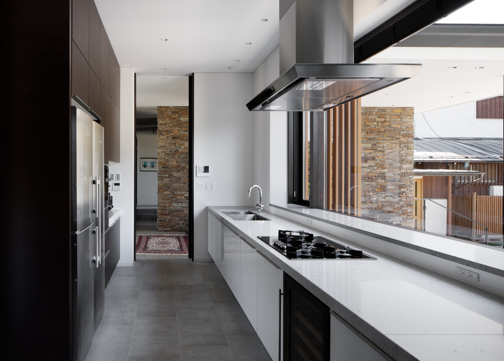 Diseño de cocina lineal contemporánea con fregadero de doble seno, armarios con paneles lisos, puertas de armario blancas, salpicadero blanco, una isla y suelo gris