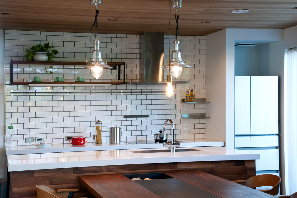 Cette photo montre une grande cuisine linéaire moderne avec une crédence en carreau de porcelaine et un plan de travail blanc.