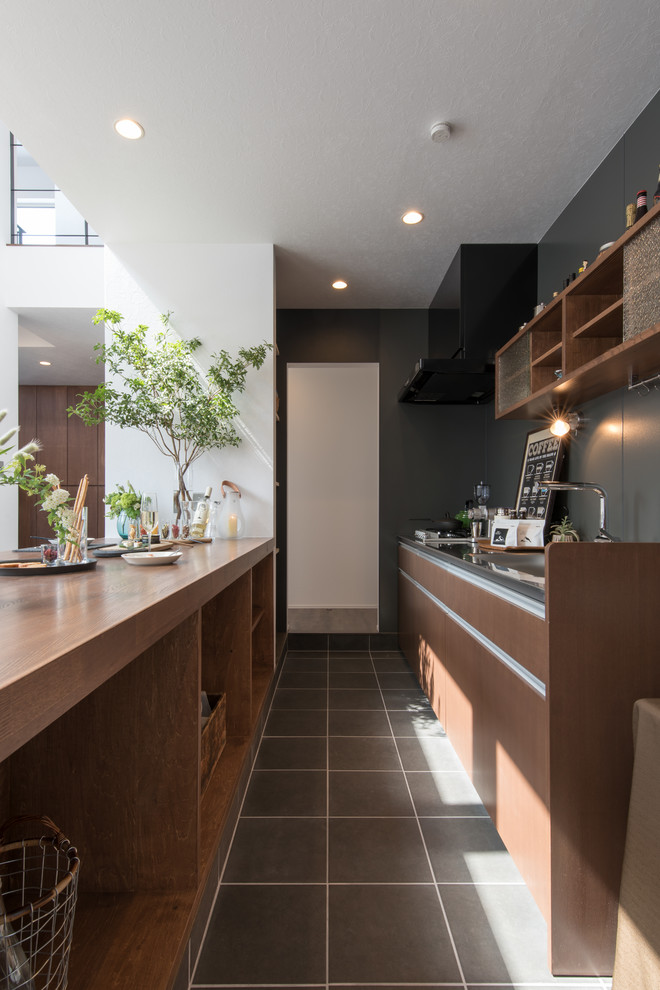 На фото: параллельная кухня в современном стиле с плоскими фасадами, темными деревянными фасадами, полуостровом, серым полом и одинарной мойкой