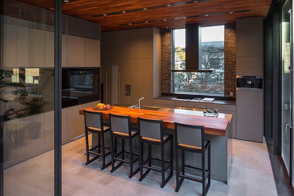 Galley kitchen in Tokyo with a submerged sink, flat-panel cabinets, grey cabinets, stainless steel worktops, black appliances and an island.