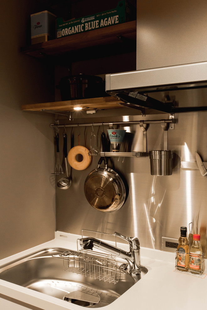 This is an example of a modern kitchen in Kyoto with white cabinets, composite countertops, white splashback, black appliances and plywood flooring.