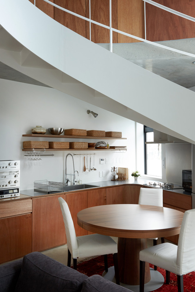 Immagine di una cucina industriale con lavello integrato, ante lisce, ante in legno scuro e top in acciaio inossidabile