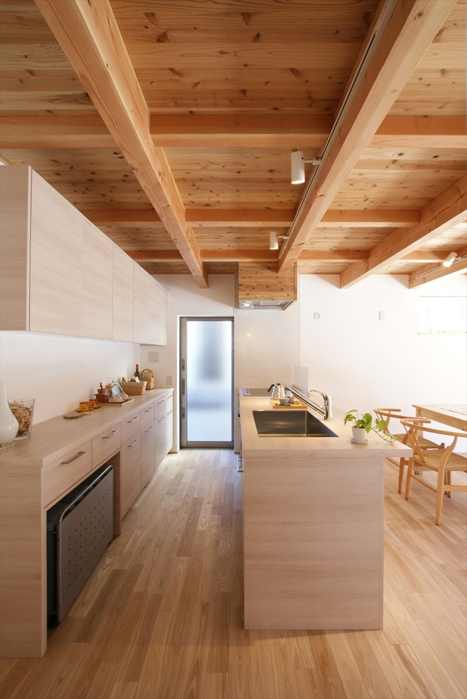 Пример оригинального дизайна: прямая кухня-гостиная в скандинавском стиле с одинарной мойкой, плоскими фасадами, светлыми деревянными фасадами, деревянной столешницей, светлым паркетным полом, полуостровом, бежевым полом и бежевой столешницей