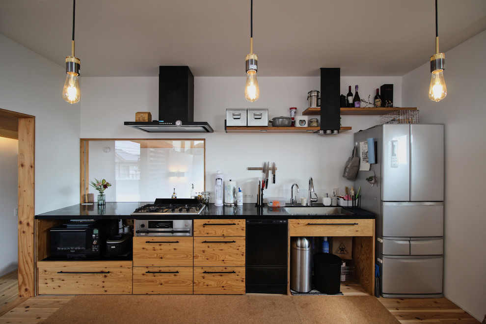 Idéer för ett modernt svart linjärt kök, med en enkel diskho, släta luckor, skåp i mellenmörkt trä, vitt stänkskydd, mellanmörkt trägolv, en halv köksö och brunt golv